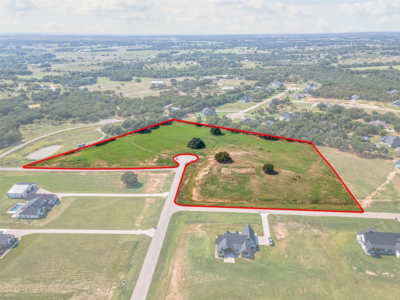 Rolling ag-exempt acreage with scattered oak trees at sunrise near Weatherford, Texas